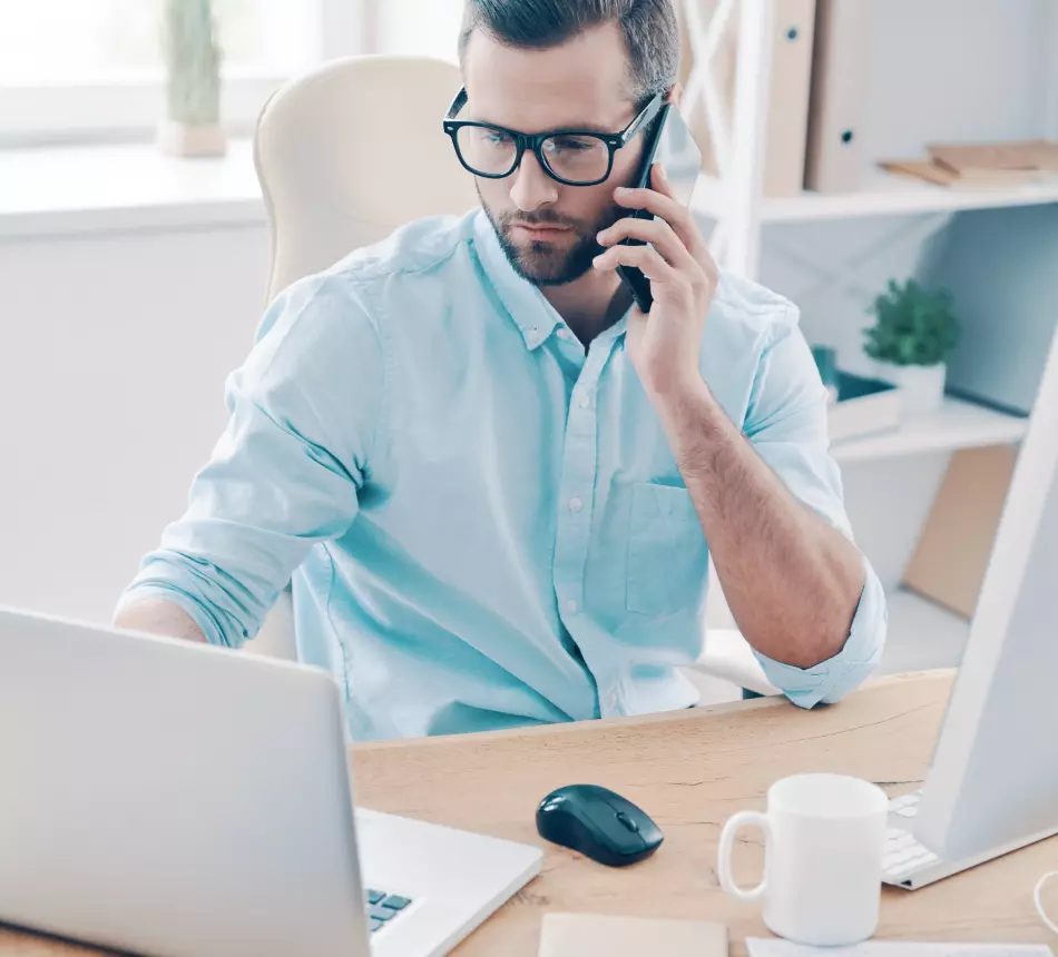 A man in glasses is talking on the phone